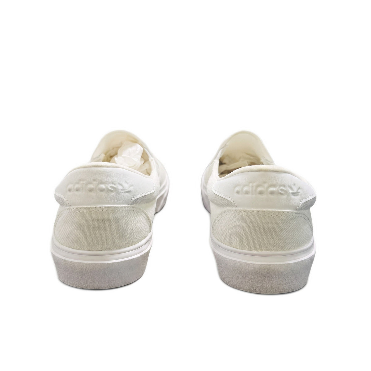 Rear heel view of both white slip-on sneakers showing the embossed trefoil logo.