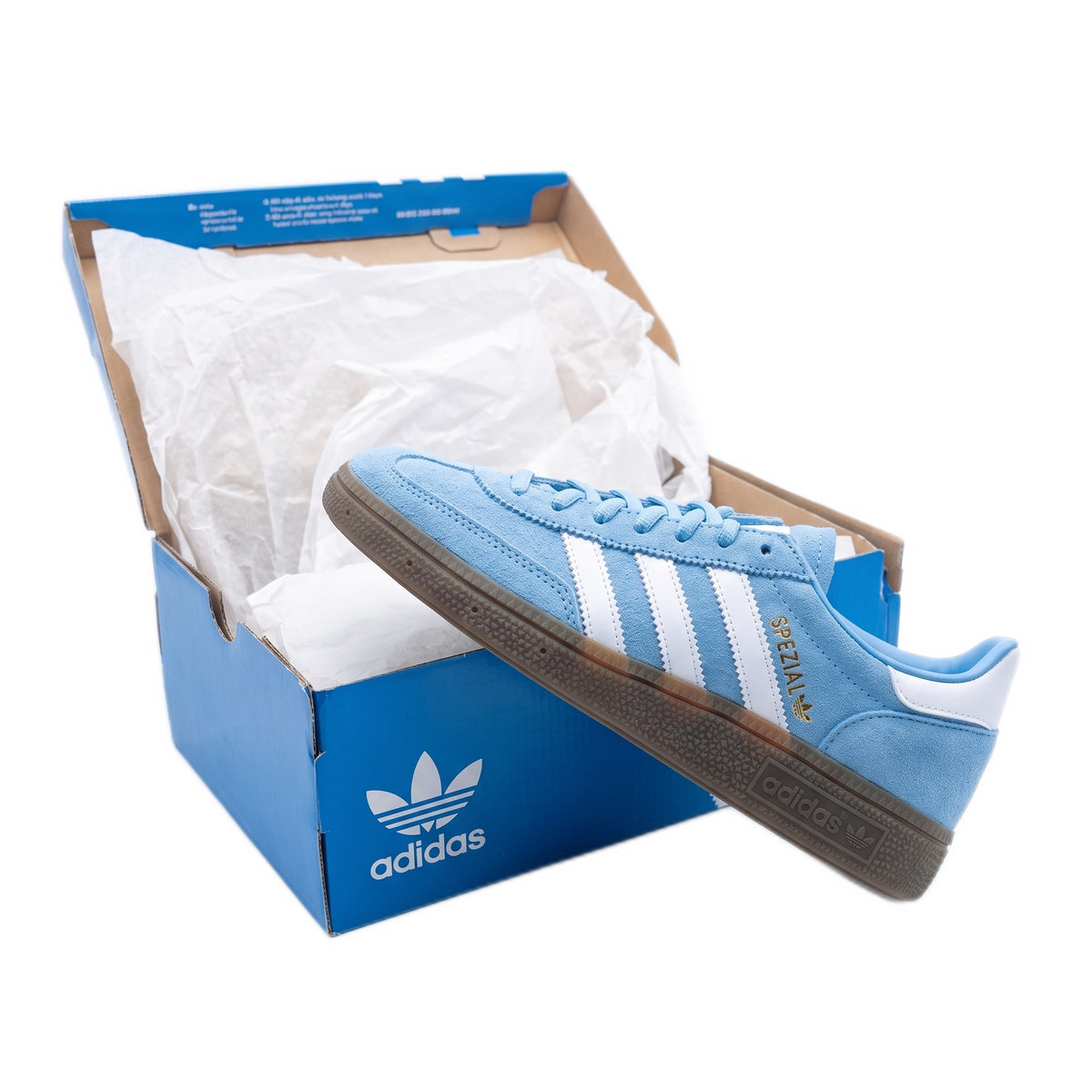 Side view of one shoe resting diagonally against its open blue box with tissue paper.
