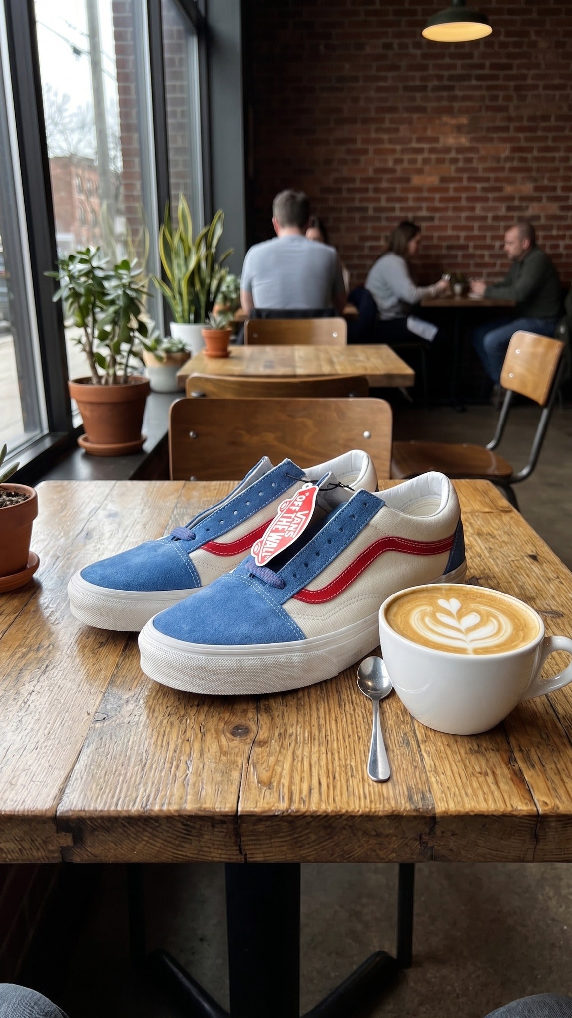 Lifestyle view of the shoes on a wooden table next to a cup of coffee.