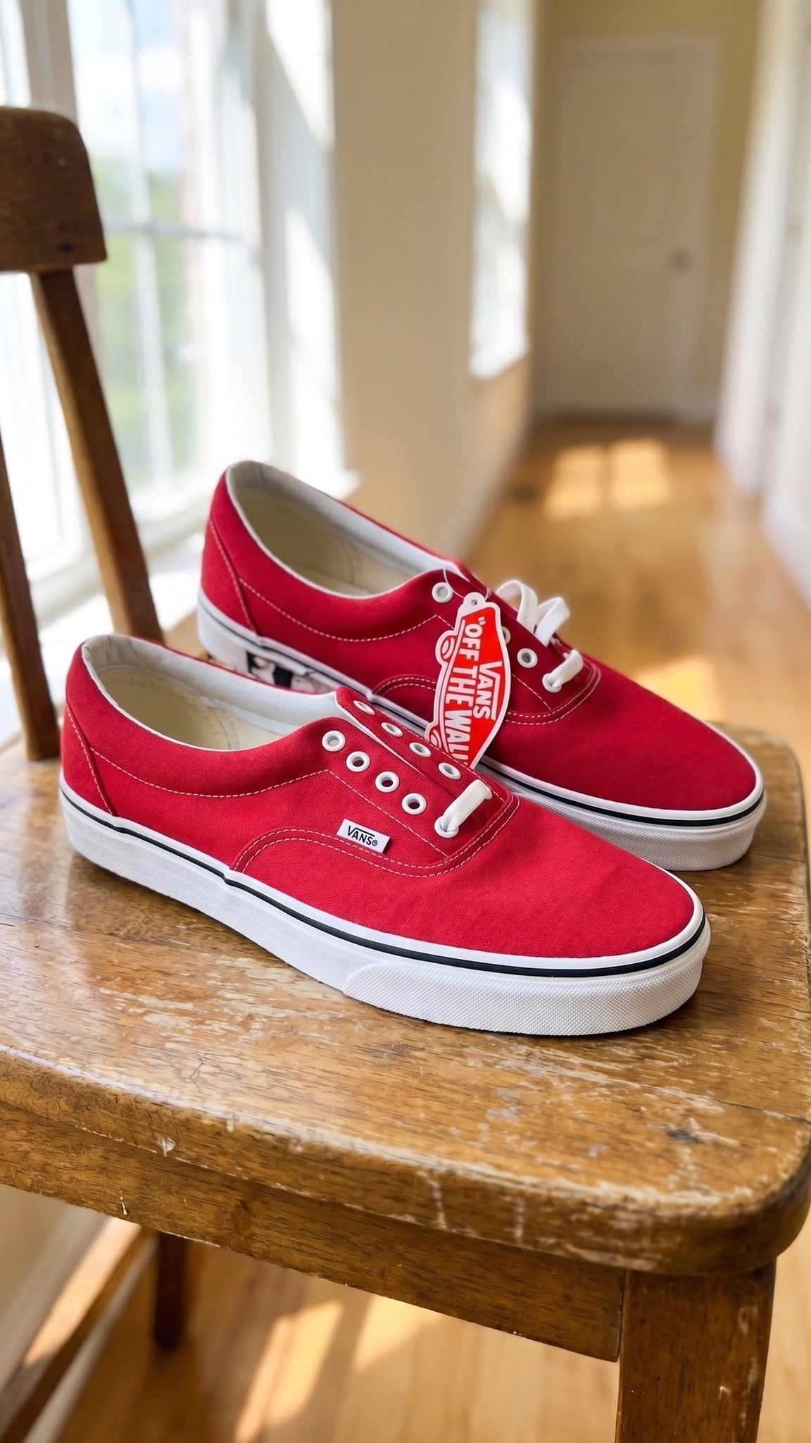 Three-quarter view of the pair of red sneakers placed on a wooden chair.