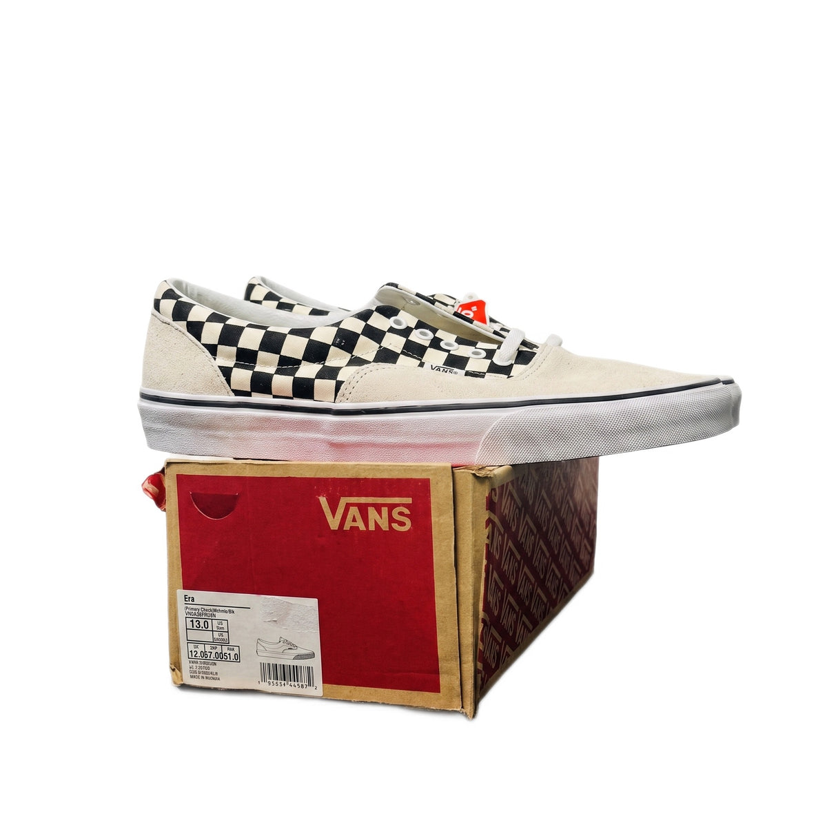 Side profile of one sneaker resting on its red and brown Vans shoebox.