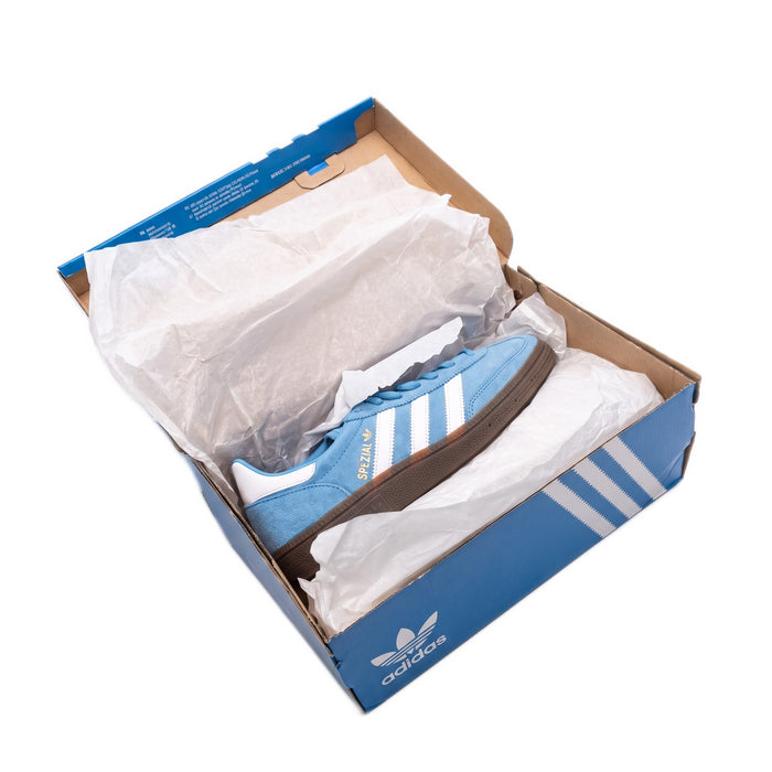 High-angle view of a single shoe resting inside the open blue box with tissue paper.