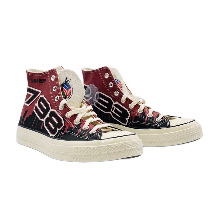 Three-quarter view of both high-top sneakers, showing red, black, and cream graphics.