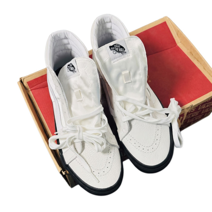 Close-up top-down view of the white sneakers resting on an open red Vans shoebox.