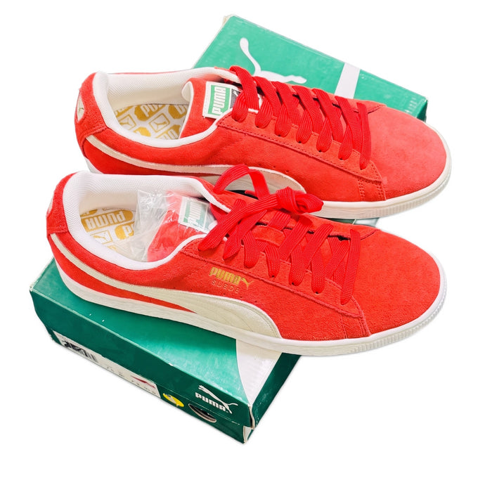 Three-quarter view of both red sneakers resting on a green Puma shoebox.