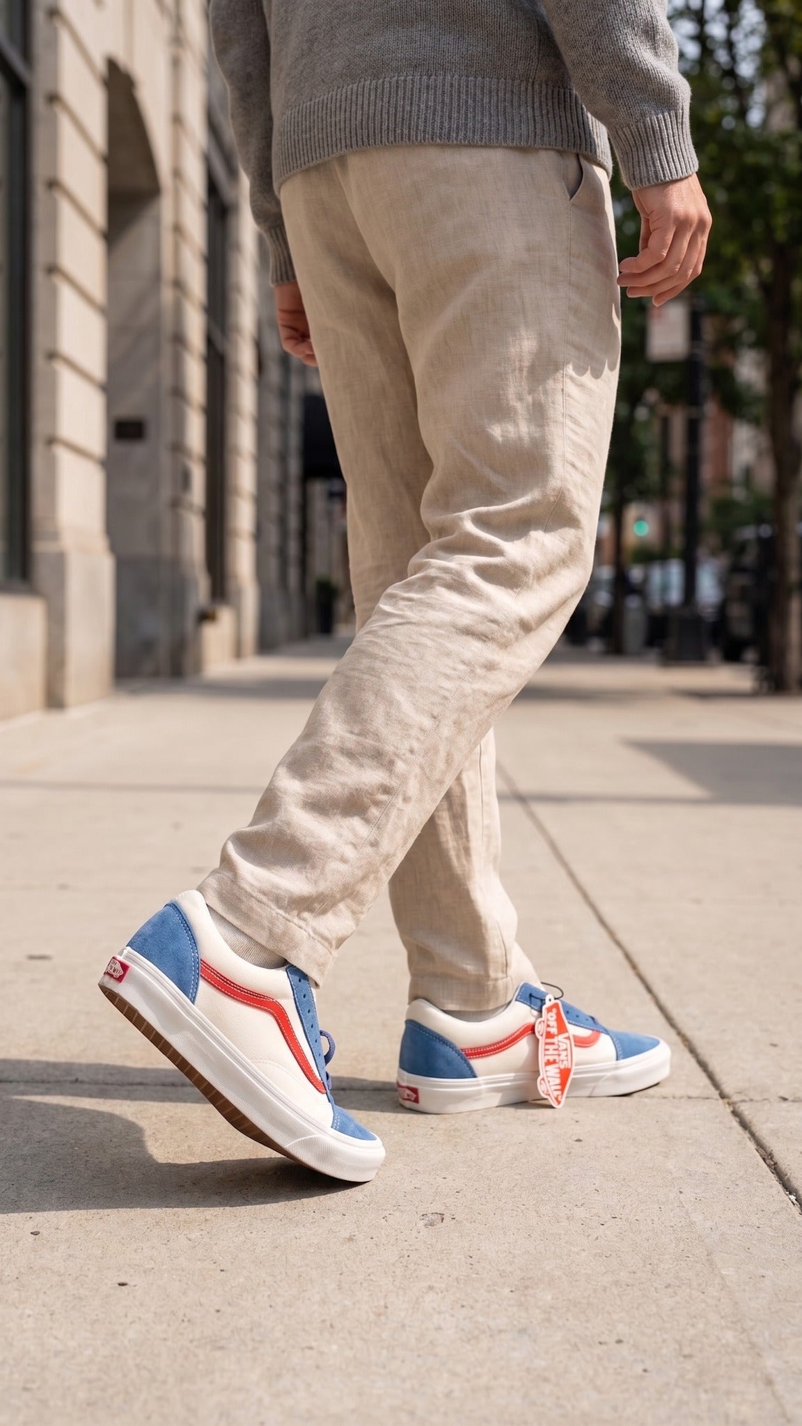 Worn view of the sneakers on feet, paired with khaki pants on a sidewalk.