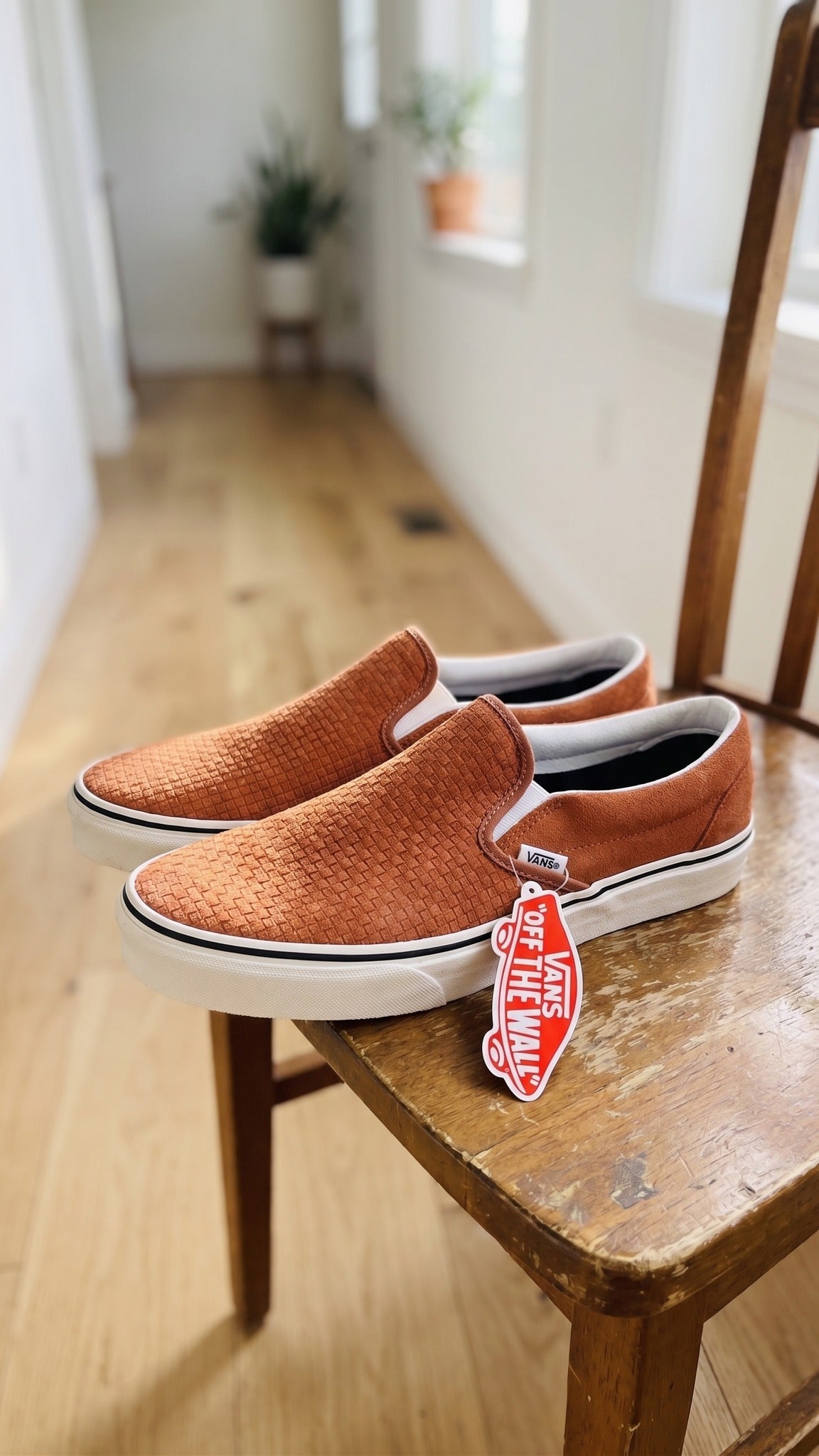 Three-quarter view of the shoes on a wooden chair in an indoor setting.