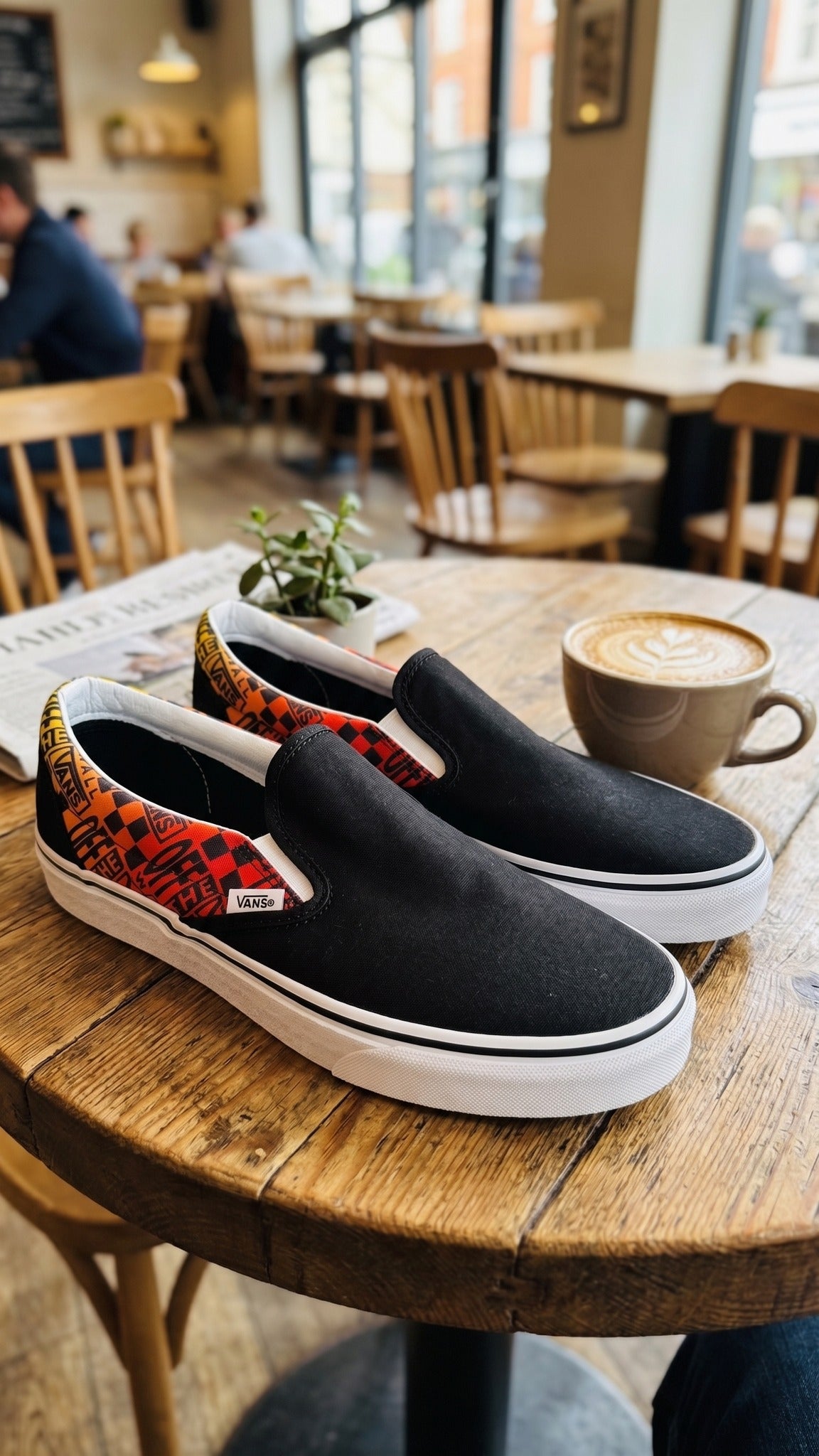 Three-quarter view of both shoes sitting on a round wooden table in a cafe setting.