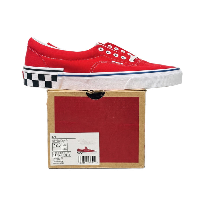 Side profile of one red sneaker resting on its original shoe box.