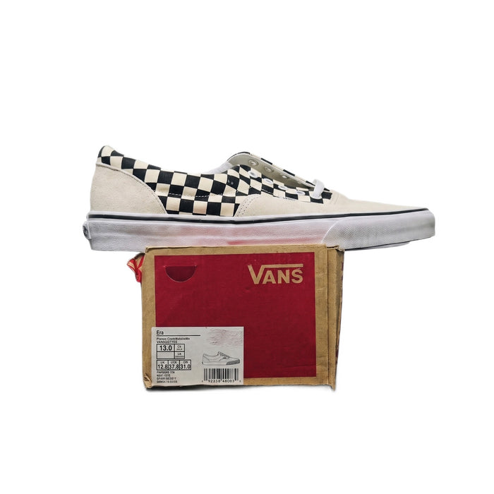 Straight-on side profile of one sneaker sitting on its red Vans shoebox.